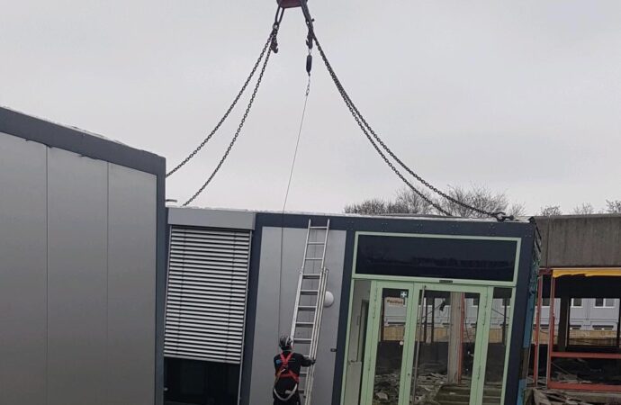 Ein Container ist am Kranseil befestigt.